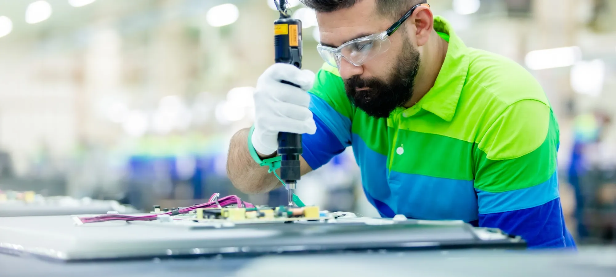Technician performing hands-on maintenance on factory machinery.